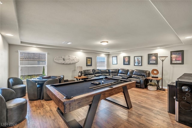 recreation room featuring billiards, a tray ceiling, and light hardwood / wood-style flooring