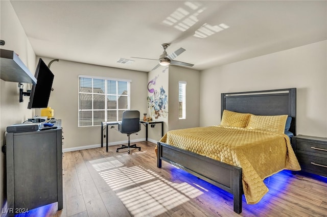 bedroom with ceiling fan, light hardwood / wood-style flooring, and multiple windows