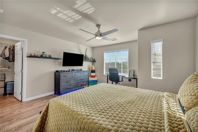 bedroom with ceiling fan, light hardwood / wood-style flooring, a spacious closet, and a closet