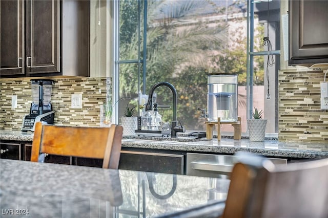 kitchen featuring sink, tasteful backsplash, stone counters, and dark brown cabinetry