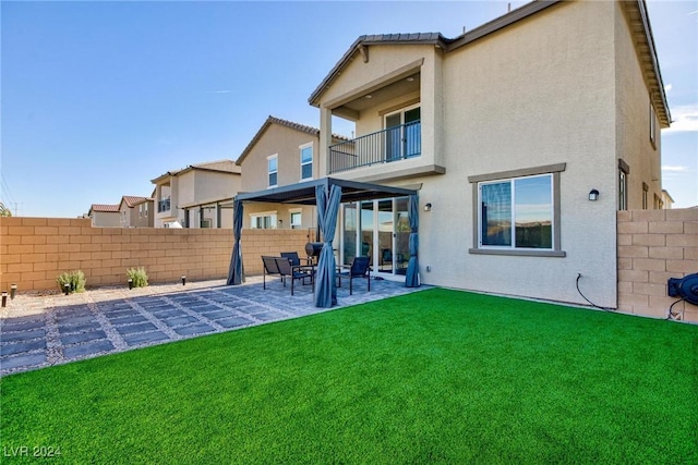 back of property with a yard, a patio, and a balcony