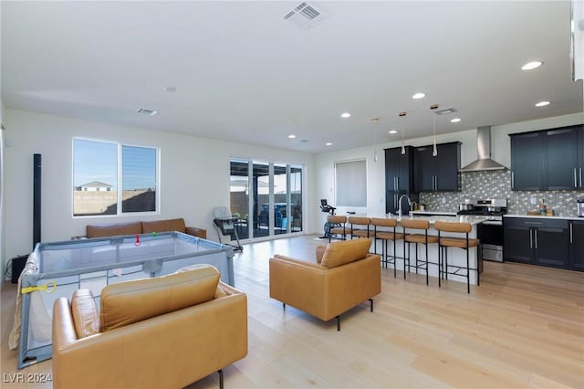 living room with light wood-type flooring, a healthy amount of sunlight, and sink