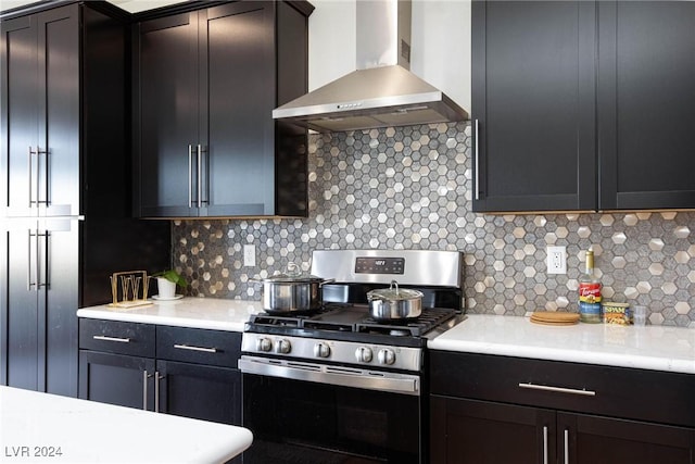 kitchen featuring stainless steel gas range oven, wall chimney range hood, and tasteful backsplash