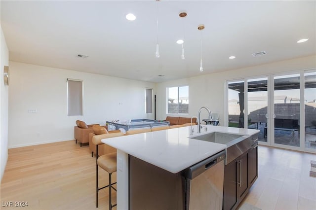 kitchen with sink, dishwasher, light hardwood / wood-style flooring, an island with sink, and pendant lighting