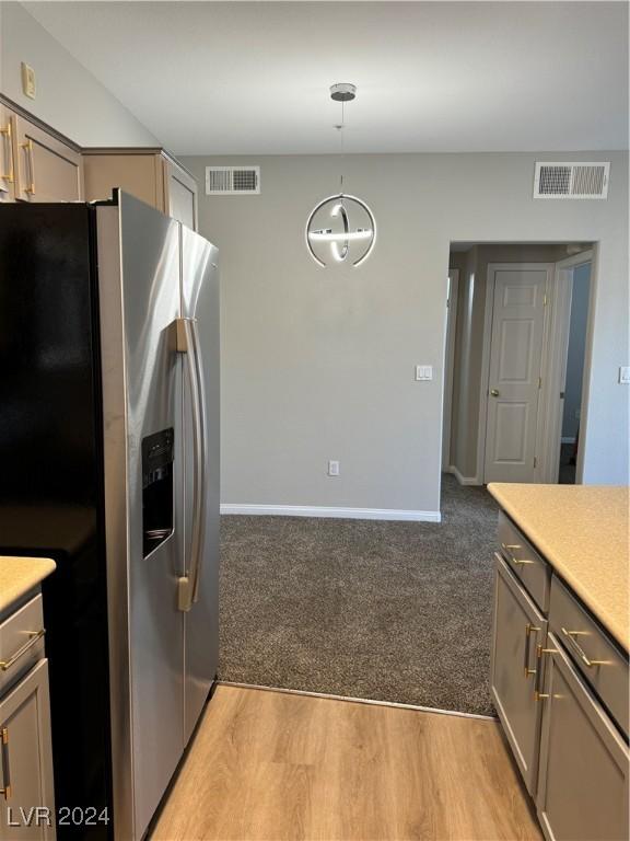 kitchen with gray cabinetry, stainless steel fridge, pendant lighting, and light wood-type flooring