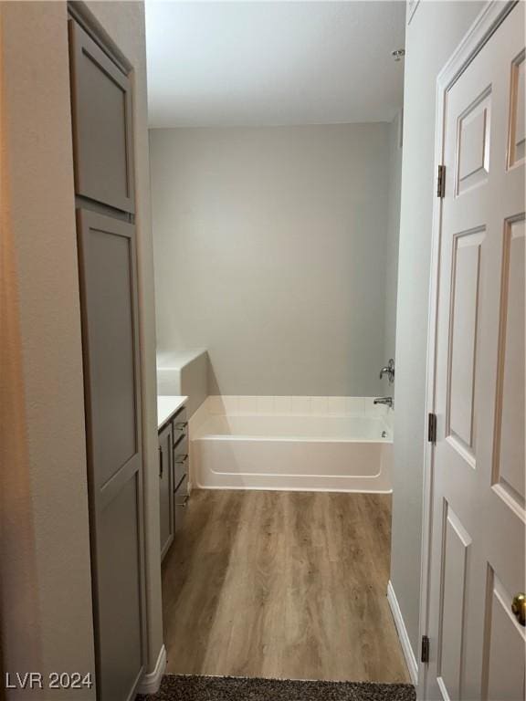 bathroom featuring hardwood / wood-style floors, vanity, and a bath