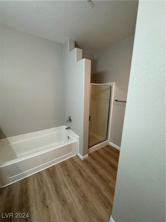 bathroom featuring plus walk in shower and wood-type flooring