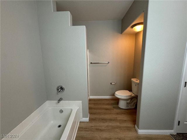 bathroom with a bathing tub, toilet, and hardwood / wood-style flooring