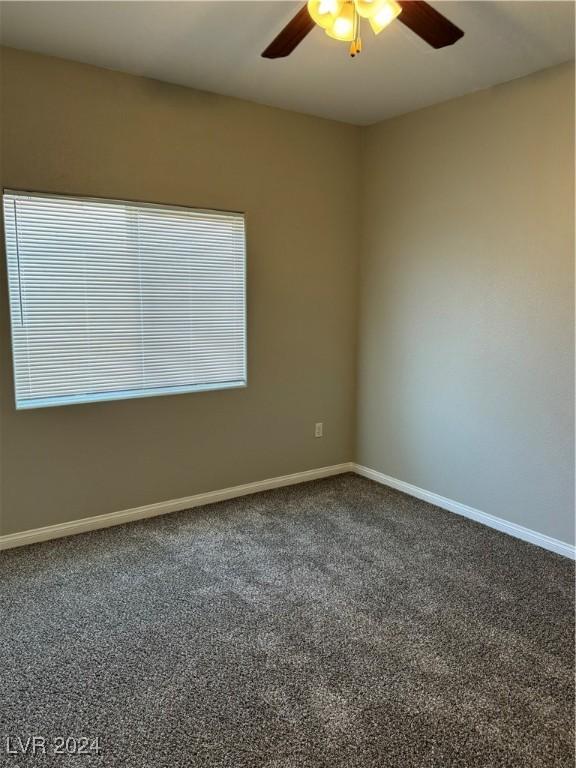 spare room with dark carpet and ceiling fan