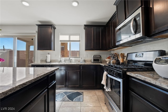 kitchen featuring light tile patterned floors, sink, stainless steel appliances, light stone counters, and dark brown cabinetry