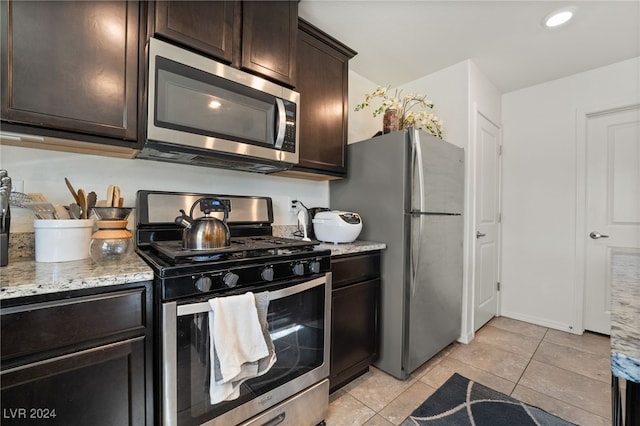 kitchen featuring appliances with stainless steel finishes, light stone countertops, dark brown cabinets, and light tile patterned floors