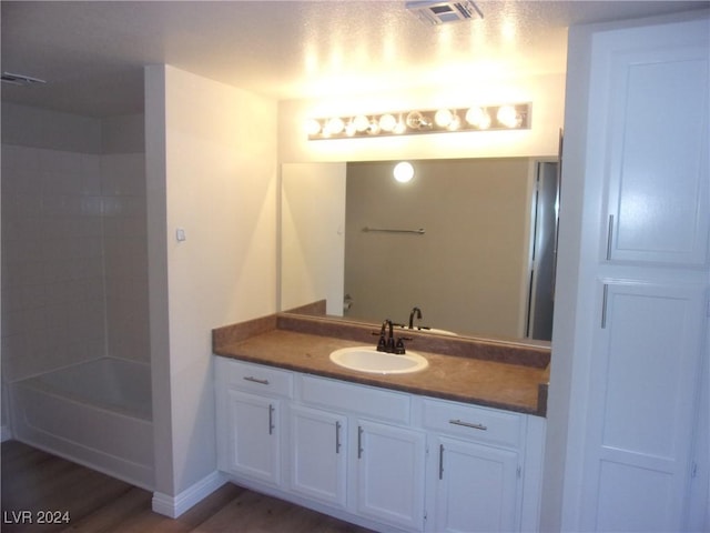 bathroom featuring wood-type flooring, vanity, and shower / bath combination