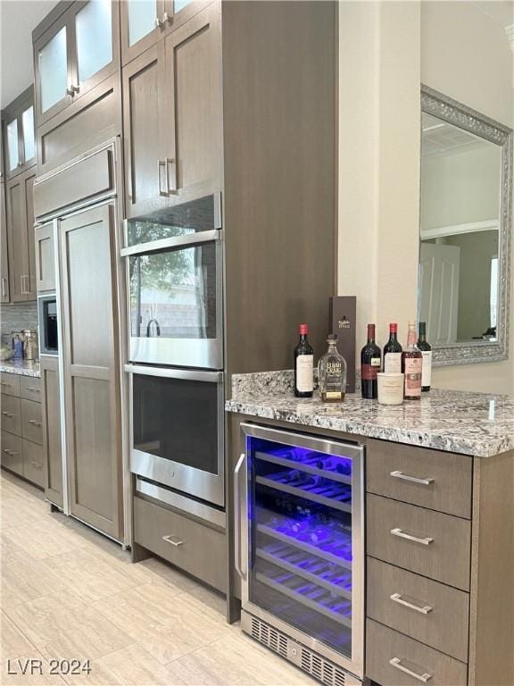 kitchen with light stone countertops, paneled built in fridge, wine cooler, and double oven