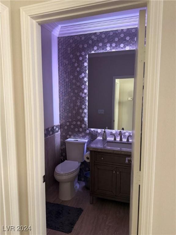 bathroom with vanity, crown molding, wood-type flooring, and toilet