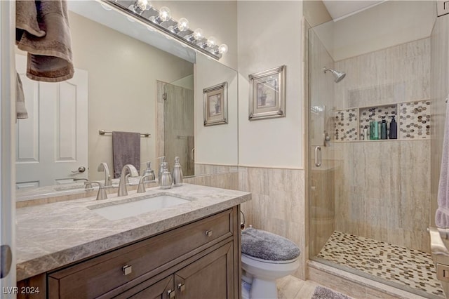 bathroom with tile walls, vanity, toilet, and walk in shower