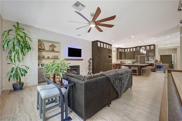 living room with light hardwood / wood-style floors, ceiling fan, and built in shelves