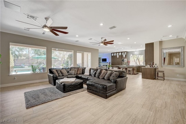 living room with ornamental molding and ceiling fan