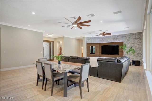 dining area featuring ceiling fan, ornamental molding, a stone fireplace, and light wood-type flooring