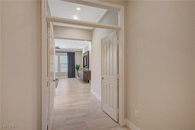 hall with ornamental molding and light hardwood / wood-style floors