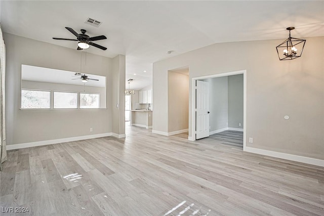 spare room with lofted ceiling, light hardwood / wood-style flooring, and ceiling fan with notable chandelier