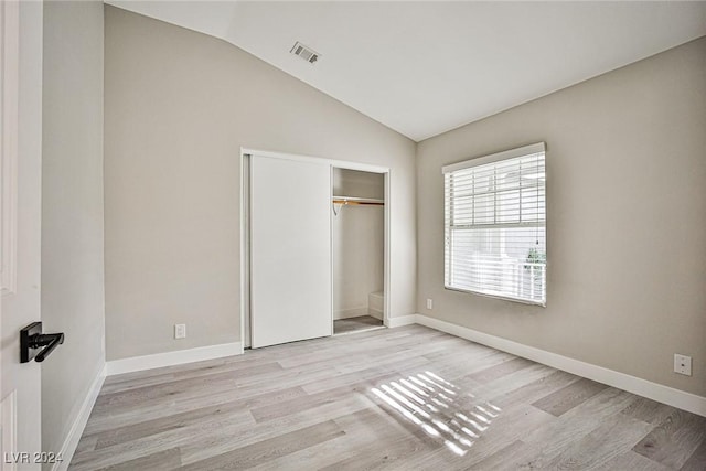 unfurnished bedroom with a closet, lofted ceiling, and light wood-type flooring