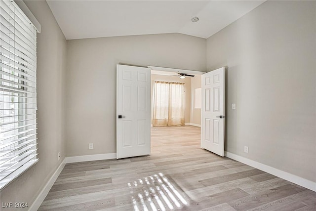 unfurnished bedroom with vaulted ceiling, light wood-type flooring, and multiple windows