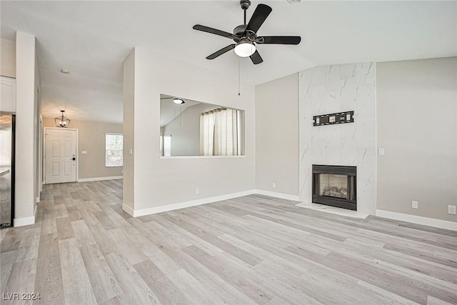 unfurnished living room featuring ceiling fan, a fireplace, lofted ceiling, and light wood-type flooring