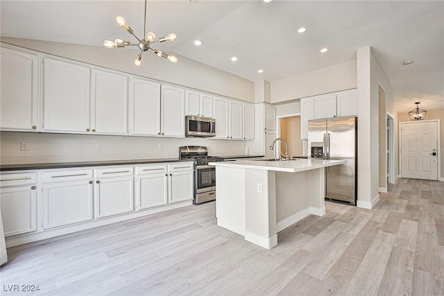 kitchen featuring appliances with stainless steel finishes, sink, decorative light fixtures, light hardwood / wood-style floors, and an island with sink