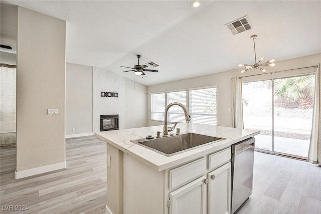 kitchen featuring stainless steel dishwasher, sink, white cabinetry, lofted ceiling, and an island with sink