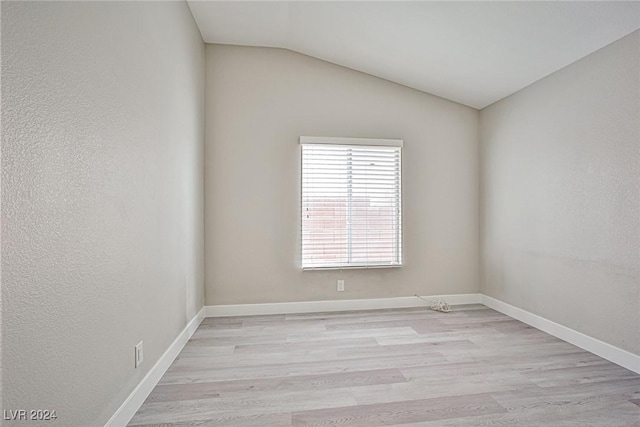 empty room with light hardwood / wood-style floors and vaulted ceiling