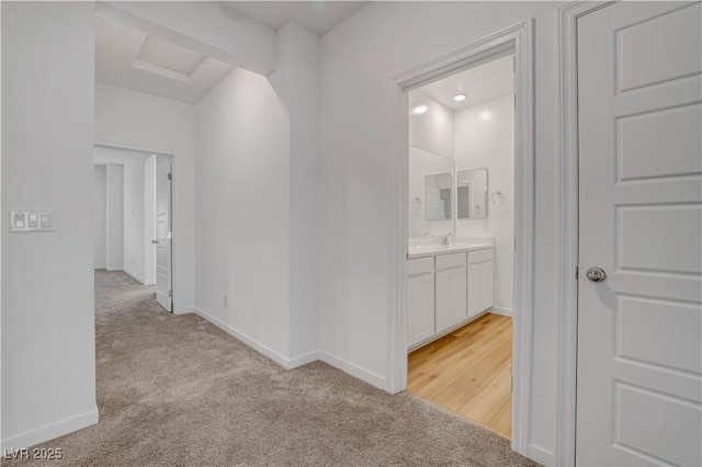 corridor with light colored carpet and sink