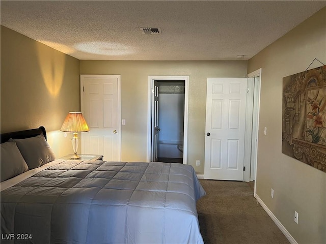 carpeted bedroom featuring a textured ceiling and ensuite bath