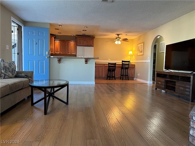 living room featuring ceiling fan, a textured ceiling, and hardwood / wood-style flooring