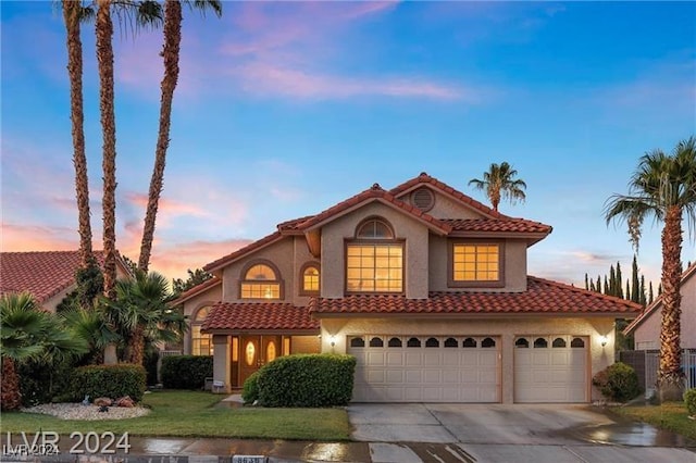 mediterranean / spanish-style home featuring a garage and a yard