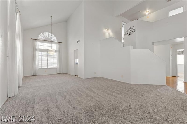 unfurnished living room with light colored carpet and high vaulted ceiling