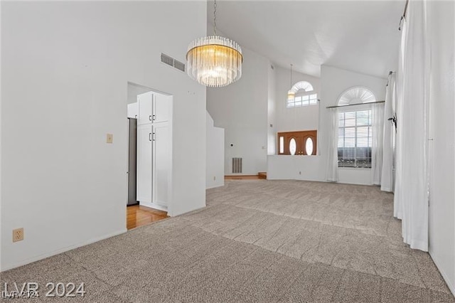 unfurnished living room featuring light carpet, high vaulted ceiling, and a notable chandelier