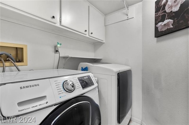 clothes washing area with washer and clothes dryer and cabinets