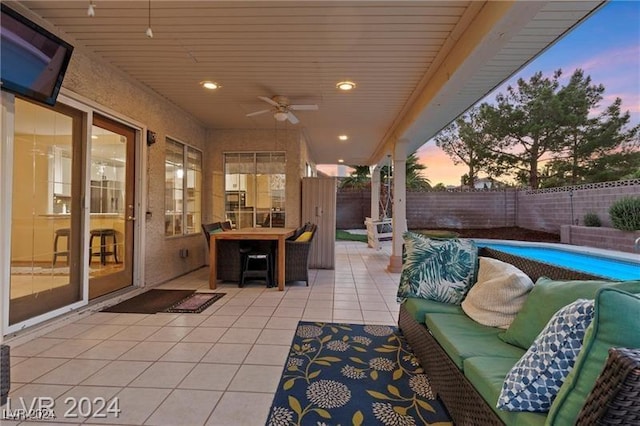 patio terrace at dusk with a fenced in pool, ceiling fan, and an outdoor living space