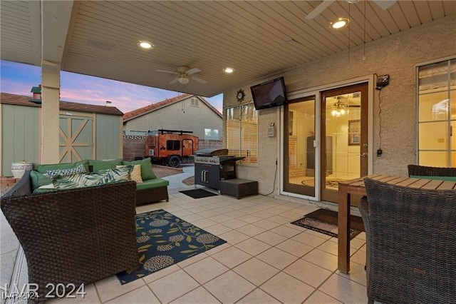 patio terrace at dusk featuring ceiling fan, a shed, and an outdoor living space