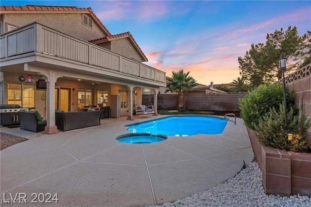 pool at dusk with an outdoor living space, a patio area, and an in ground hot tub