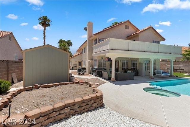 rear view of house with outdoor lounge area, a patio, a balcony, and a pool with hot tub