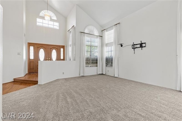 foyer entrance featuring light carpet and high vaulted ceiling