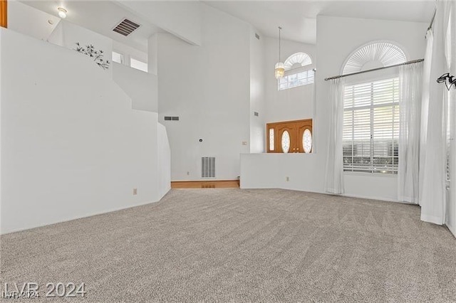 unfurnished living room featuring carpet floors and a high ceiling