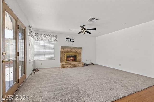 living room with ceiling fan, wood-type flooring, and a brick fireplace