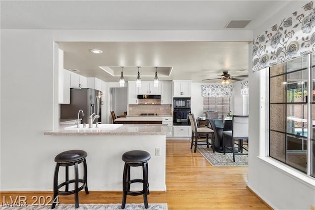 kitchen featuring kitchen peninsula, ceiling fan, white cabinets, and black appliances