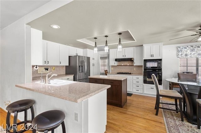 kitchen featuring kitchen peninsula, sink, black appliances, light hardwood / wood-style floors, and a kitchen island