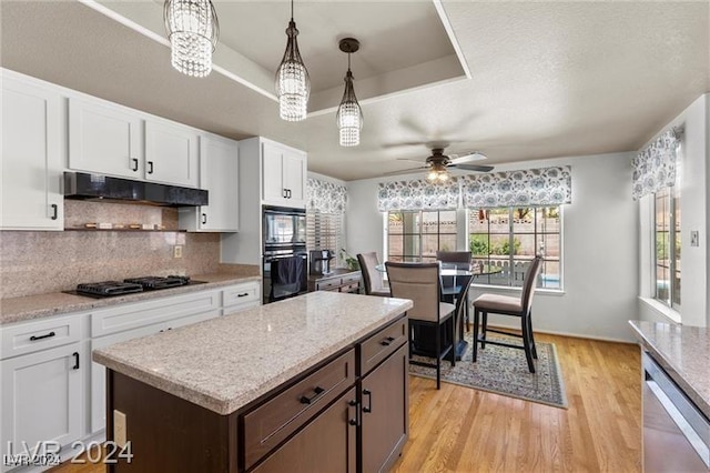 kitchen featuring black appliances, ceiling fan with notable chandelier, decorative light fixtures, light hardwood / wood-style floors, and white cabinetry