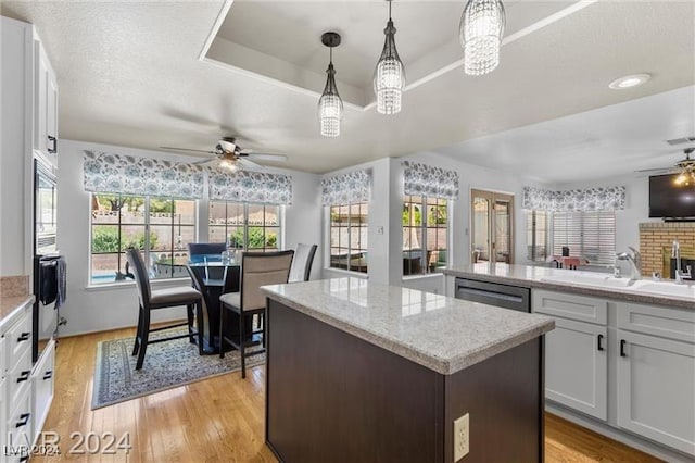 kitchen featuring white cabinetry, ceiling fan, sink, light hardwood / wood-style flooring, and decorative light fixtures