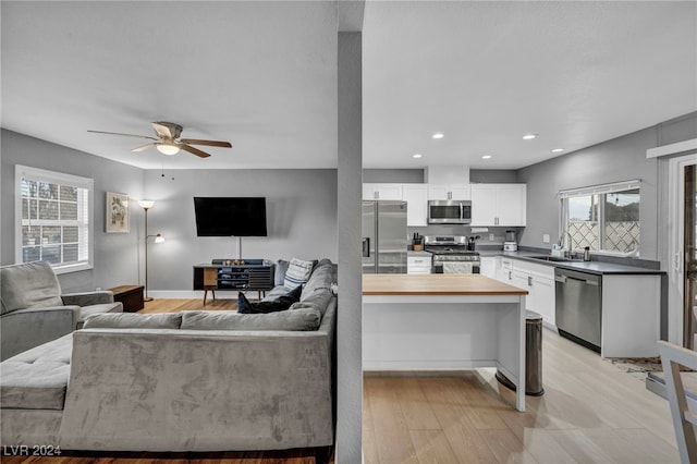 living room with ceiling fan, sink, and light wood-type flooring