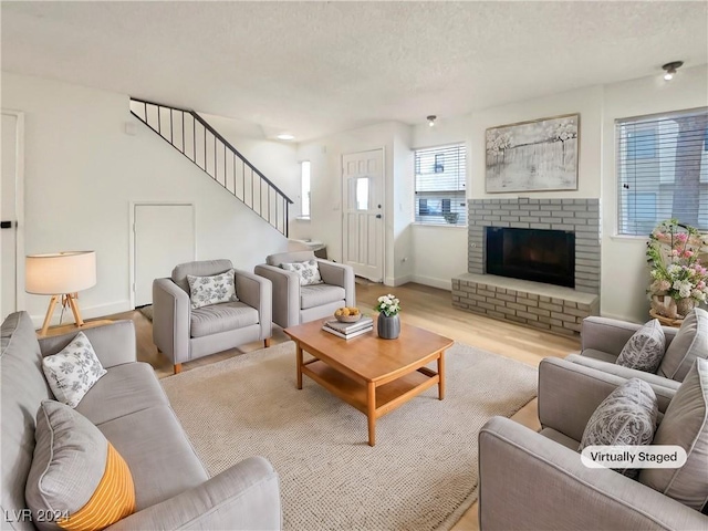 living room with a fireplace, a textured ceiling, and light wood-type flooring